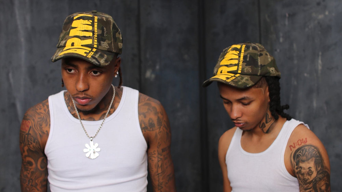 Two models in Gouge Worldwide ARMY camo caps and white tanks